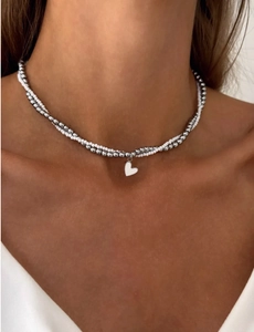 Close-up of double-layer beaded necklace featuring a white heart pendant and silver beads