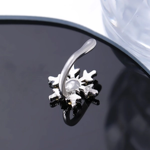 Macro shot of silver snowflake ear cuff with central pearl inlay on reflective surface