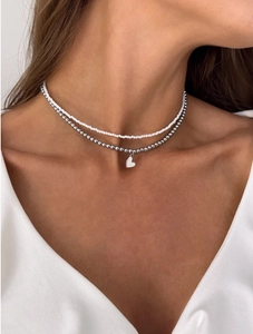 Close-up of double-layered beaded necklace with a heart pendant on a female model