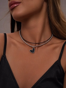 Close-up of double-layered necklace featuring black beads and a heart pendant