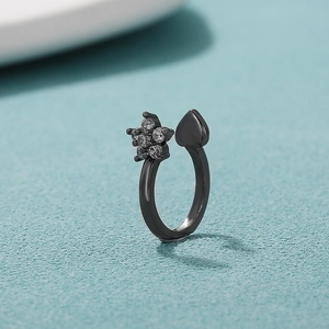 Close-up of a black open ring with zircon flower and heart shapes on a blue background