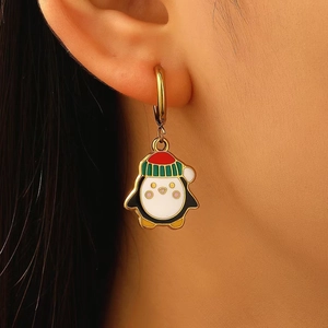 Primo piano di un orecchino a cerchio dorato con ciondolo a pinguino in smalto colorato