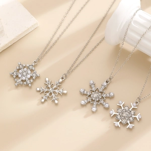 Close-up of four snowflake necklaces with rhinestones and pearls on elegant stone props