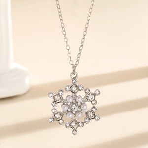 Close-up of snowflake pendant necklace with white rhinestones and pearls on beige background