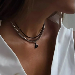 Double-layered necklace with black heart pendant and silver beaded chain on neck