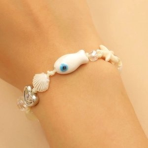 Detail of summer beach bracelet featuring ceramic starfish, fish charms, and evil eye beads