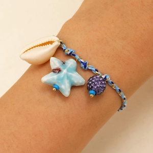 Detail of handwoven nautical bracelet with shell, ceramic starfish and purple rhinestone charm