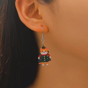 Close-up of a model wearing a cute cartoon cat earring with a festive green polka dot dress
