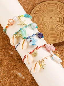 Close-up of four handmade woven ocean-themed bracelets with starfish and shell charms