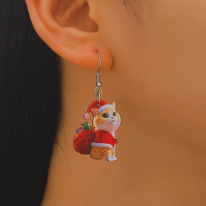 Detailed view of festive orange cat earring with Christmas hat and gift sack decor