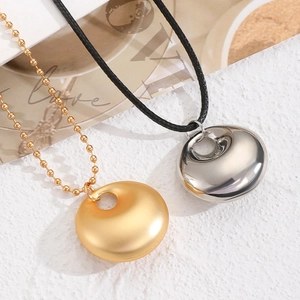 Détail de pendentifs ronds géométriques en or mat et argent poli de style minimaliste