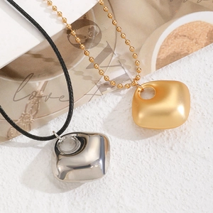 Détail de pendentifs carrés irréguliers minimalistes en or brossé et argent poli