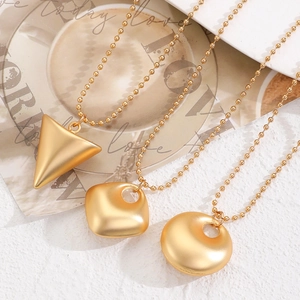 Collier géométrique minimaliste en or mat avec pendentifs ronds carrés et triangles brossés