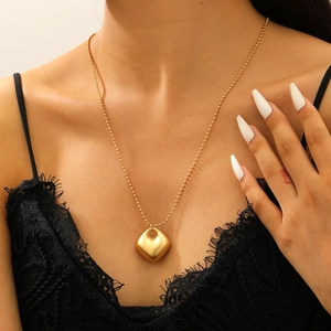 Gros plan d'un collier doré avec pendentif géométrique brossé sur une chaîne à billes