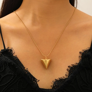 Détail d'un collier doré avec pendentif conique et finition mate texturée