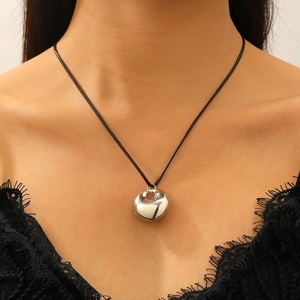 Pendentif géométrique argent poli sur cordon noir vue rapprochée sur le cou d'un modèle