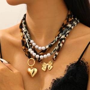 Vue macro du collier multicouche à motif léopard avec pendentifs cœur et nœud doré