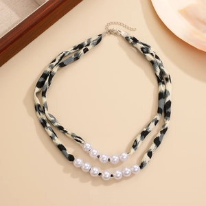 Détail d'un collier double épaisseur en tissu léopard avec perles blanches et fermoir métal