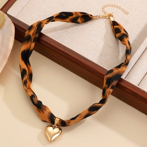 Gros plan du collier en ruban léopard et pendentif cœur doré dans un coffret cadeau