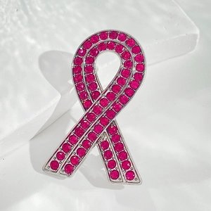 Macro detail of silver alloy pink rhinestone awareness ribbon brooch with shiny crystals