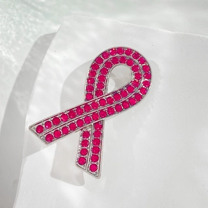 Macro shot of awareness ribbon brooch with sparkling pink rhinestones on white stone base
