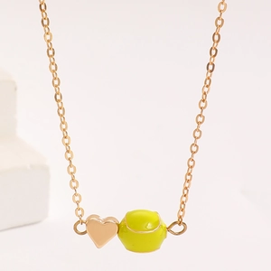 Detailaufnahme eines goldenen Herzanhängers und neon-gelben Tennisball-Charms an einer Kette