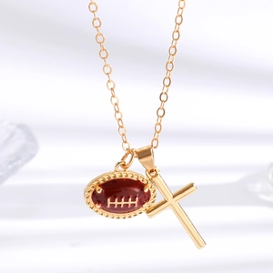 Detail einer Goldkette mit rotem Football-Anhänger und Kreuz auf weißem Stoff