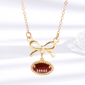 Makroaufnahme der Goldkette mit rotem Oval-Rugby-Anhänger und feiner Schleife am Glied