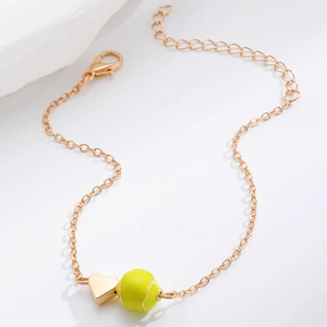 Detailaufnahme des goldenen Armbands mit Herzanhänger und neongrünem Tennisball-Anhänger