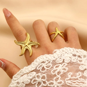 Detailed view of 18K gold plated starfish rings with textured finish on silk background