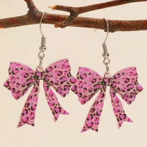 Detailed macro of acrylic leopard print bow earrings hanging on a natural branch