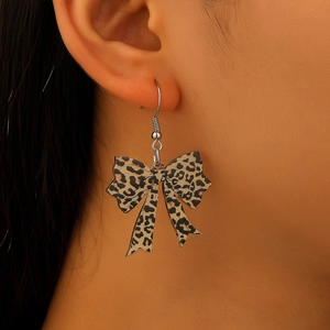 Close-up of leopard print bow earrings showing the stylish acrylic design and silver ear hooks