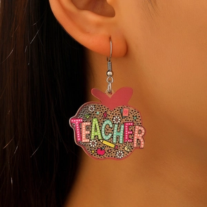 Detailed macro shot of apple-shaped acrylic earrings with leopard print and teacher text