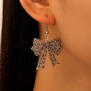 Close-up of leopard print bow earrings with heart details on female model