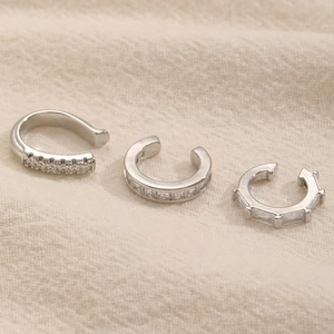 Dettaglio macro di tre ear cuff in argento con brillanti zirconi incastonati