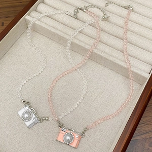Detail van vintage camera hangers met imitatieparels en strass op kralen kettingen