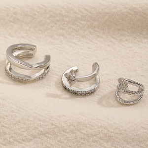 Dettaglio di tre ear cuff in argento con pendenti a stella e zirconi scintillanti