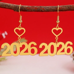 Detail van glitter gouden 2026 oorbellen met hartvorm op een feestelijke rode achtergrond