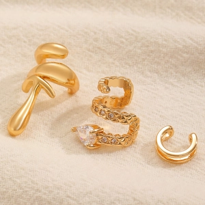 Set di tre ear cuff geometrici placcati in oro con strass su sfondo materico