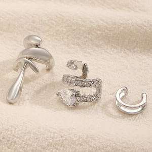 Dettaglio di un set di 3 ear cuff argentati con zirconi e forme fluide geometriche