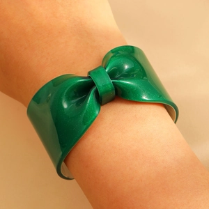 Macro detail of sparkly dark green resin bow bracelet featuring glitter and polished finish