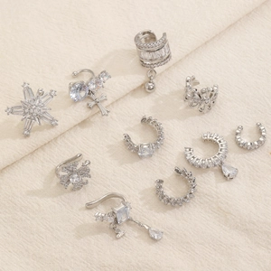Dettaglio macro del set di ear cuff geometrici in argento con zirconi su lino