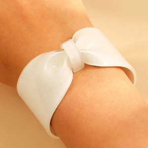 Macro detail of white glitter resin bow bracelet showing sparkling texture and wide open cuff