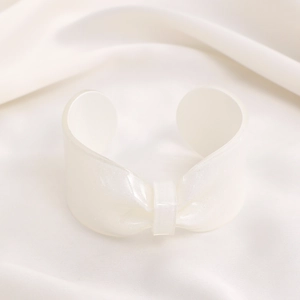 Detailed macro view of white translucent resin bow bracelet with shiny pearlescent finish