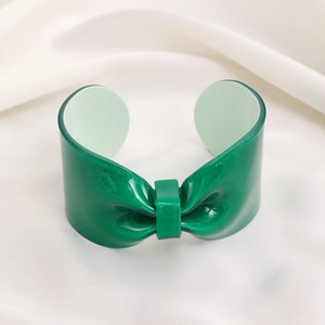 Close-up of green glitter resin bow cuff bracelet on white elegant fabric background