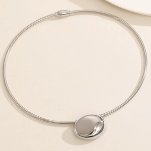 Macro view of polished oval mirror pendant on a sleek silver snake chain necklace