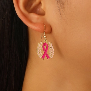 Nahaufnahme der rosa Schleife Ohrringe mit goldenen Blättern für die Brustkrebs-Aufklärung
