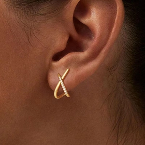 Macro view of gold X-shaped crisscross earrings with micro-pave white cubic zirconia