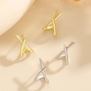 Detailed view of 3D geometric cross stud earrings in polished gold and silver finishes