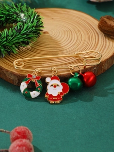 Détail d'une épingle de Noël dorée avec charms Père Noël et grelots sur bois